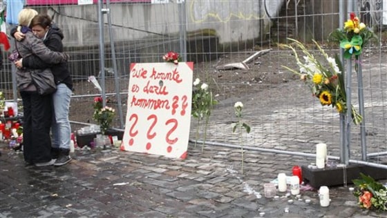Teenagers comfort each other in Duisburg, Germany, Monday at the site where 19 people were killed in a crush at the Love Parade techno festival on Saturday. Poster reads "How could it happen?"